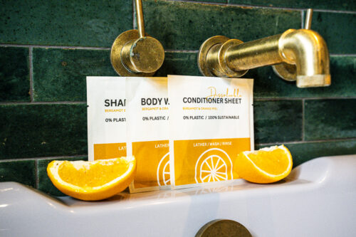 Walter Geering Toiletry Sheets in shampoo, conditioner and body wash, displayed as slim dissolvable sheets in plastic-free packaging with an orange and bergamot scent profile, designed for sustainable hotel and hospitality use.